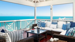 A covered outdoor seating area with a view of the ocean, furnished with wicker furniture and patterned cushions. - Villa Calypso: Ocean Access, Pool, Kayaks, & More! (Providenciales)