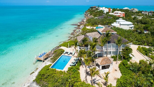 An aerial view of a coastal property with a swimming pool, beachfront, and multiple houses. - Villa Calypso: Ocean Access, Pool, Kayaks, & More! (Providenciales)