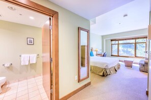 A hotel room with a bathroom, a large bed, a window, and a view of the outdoors.