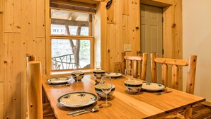 Ein Esszimmer mit einem Holztisch, gedeckt mit Tellern, Schüsseln, Weingläsern und Besteck.