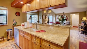 A kitchen with wooden cabinets, granite countertops, a dishwasher, and a sink. - Private Hot Tub + Deck: Breckenridge Abode! (Breckenridge)