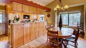 A kitchen with wooden cabinets, a central island, and a dining area with a round table and chairs. - Private Hot Tub + Deck: Breckenridge Abode! (Breckenridge)