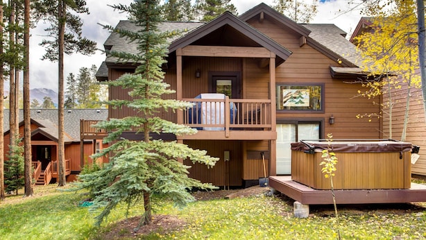 A two-story log cabin with a balcony, a hot tub, and a small tree in the yard. - Private Hot Tub + Deck: Breckenridge Abode! (Breckenridge)