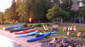 A beach with kayaks lined up and chairs arranged on the sand. - Family resort cottage 3 on Big Glen Lake, Rent 1 or 5, dock, kayaks, rowboat (Maple City)