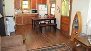 A compact kitchen with wooden cabinets, a dining table with chairs, a refrigerator, and a microwave. - Family resort cottage 3 on Big Glen Lake, Rent 1 or 5, dock, kayaks, rowboat (Maple City)