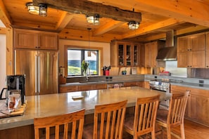 Una cocina moderna con armarios de madera, electrodomésticos de acero inoxidable y una isla grande con taburetes de bar.