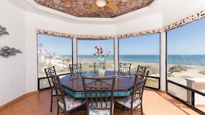 A dining area with a round table, chairs, and a view of the beach. - Whale of a Tale – Adults-Only Beachfront (Puerto Peñasco)