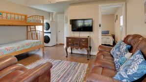 A compact living space with a bunk bed, a sofa, a television, and a washing machine. - Plantersville Cabin on 50 Acres w/ Pond & Fire Pit (Plantersville)