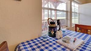 A room with a checkered tablecloth, a welcome sign, a window with a view of trees, and a whiteboard. - Plantersville Cabin on 50 Acres w/ Pond & Fire Pit (Plantersville)