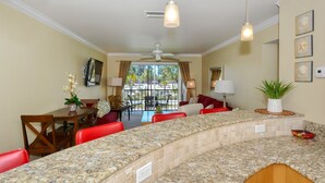 A kitchen with a granite countertop, red chairs, a dining table, and a ceiling fan. - Condo# 208 Charming Condo at La Siesta with Partial Beach Views "Your home away from home" (Sarasota)