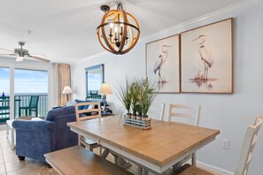 A dining area with a wooden table, chairs, a chandelier, and artwork on the wall.