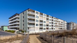 Ein mehrstöckiges Hotel mit Balkonen, einem Sandweg und einem Holzzaun.