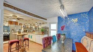 A kitchen with a dining area, a chandelier, and a wall with writing. - Bohemian Wonderland: Benicia Bungalow w/ Pergola! (Benicia)