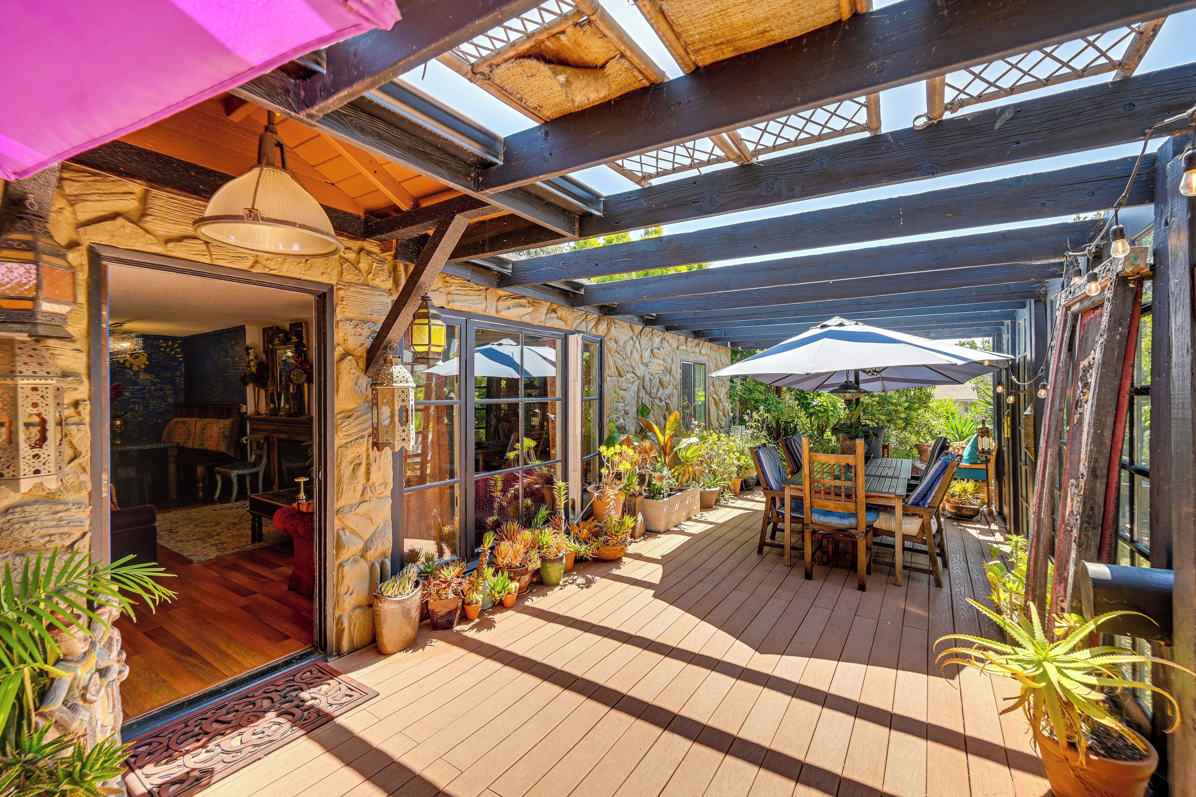 Un patio couvert doté d’un plancher en bois, de plantes en pot et de mobilier d’extérieur.