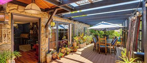 Un patio couvert doté d’un plancher en bois, de plantes en pot et de mobilier d’extérieur.