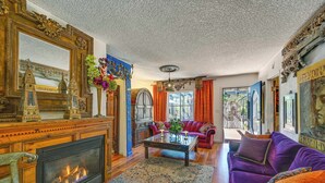 A spacious living room with a fireplace, a large mirror, and a vibrant purple sofa. - Bohemian Wonderland: Benicia Bungalow w/ Pergola! (Benicia)