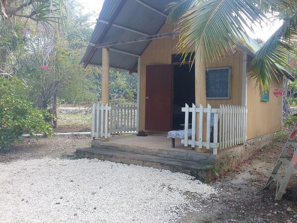 Ein kleines Holzhaus mit weißem Zaun, einer Veranda und einer Tür.