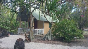 Une maison avec un toit en tôle ondulée, entourée de gravier et de verdure.