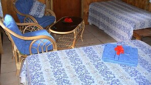 Une chambre avec deux lits simples, une petite table et deux chaises en osier.