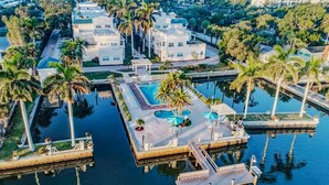 Eine Luftaufnahme eines Resorts mit mehreren Gebäuden, einem zentralen Poolbereich und umliegenden Palmen.