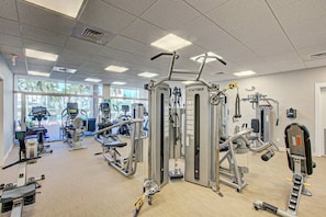 Ein Fitnessstudio mit verschiedenen Trainingsgeräten, darunter Kabelzugmaschinen und Gewichtecken.