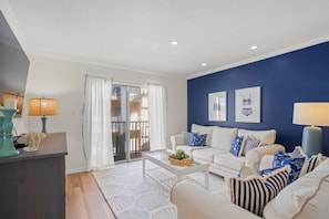 A living room with a white sofa set, a coffee table, and a blue accent wall. - Palm Bay Club Bayside Pools Hot Tub, Private Beach (Siesta Key)