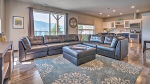 A modern living room with a sectional sofa, a dining area, and a kitchen with built-in appliances. - Modern Manson Condo w/ Pool & Lake Chelan Views! (Manson)