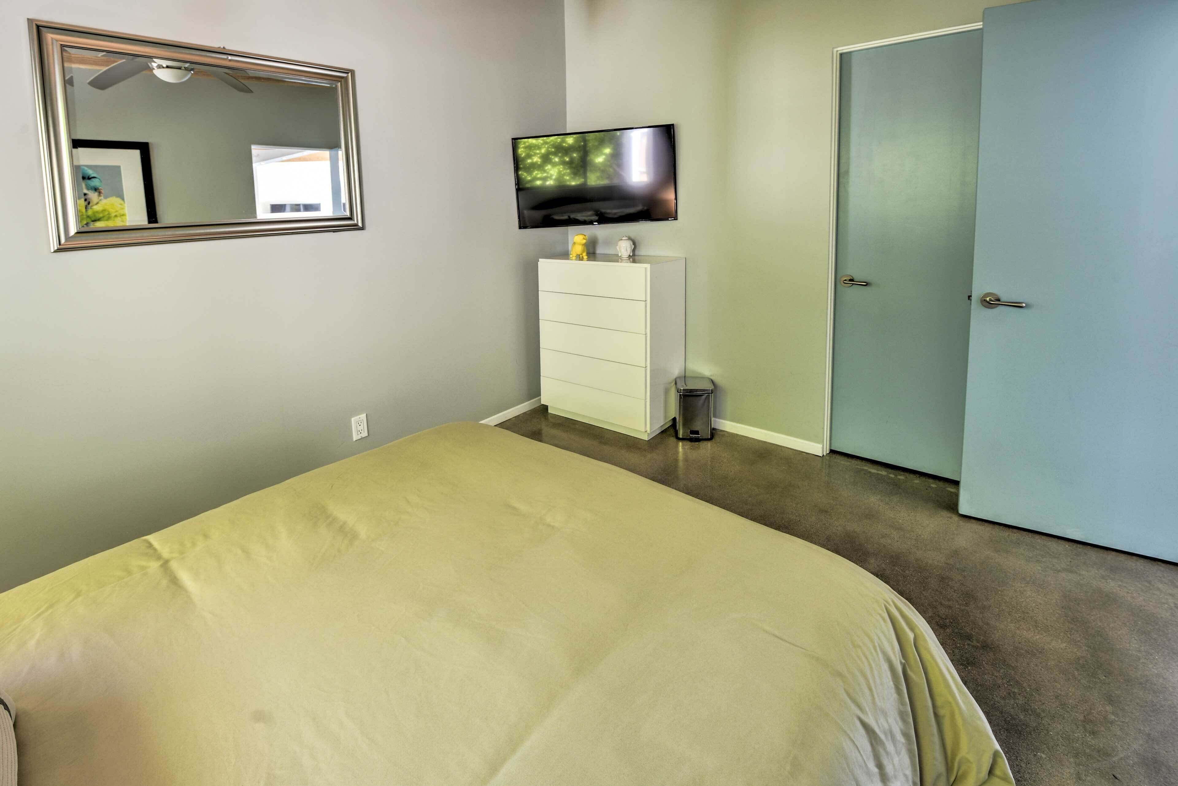 A bedroom with a bed, a dresser, a television mounted above it, and a door.