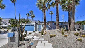 A residential property with a driveway, palm trees, cacti, and a mailbox labeled 2103.