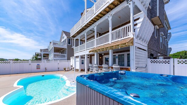 Un espace piscine avec un jacuzzi et des sièges extérieurs.