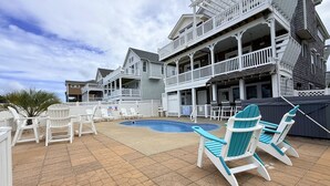 Un espace piscine avec des chaises longues et un bâtiment à deux étages doté de balcons.