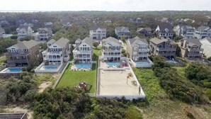 Un quartier résidentiel composé de plusieurs maisons à deux étages, chacune ayant un jardin devant et une piscine.