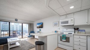 A modern apartment with a kitchen, dining area, and a living room with a large window.