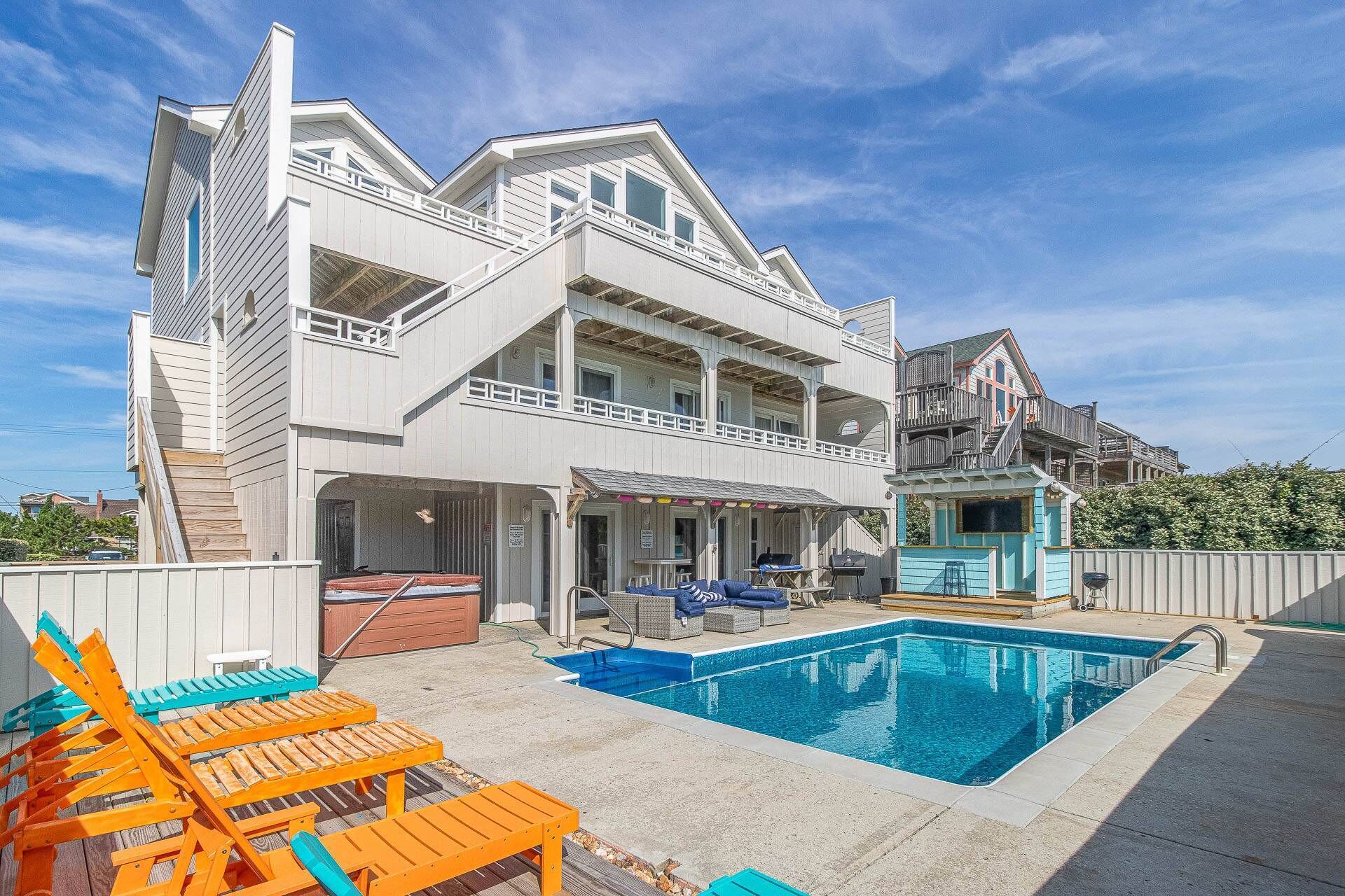 A two-story house with a swimming pool, outdoor seating, and a covered patio.
