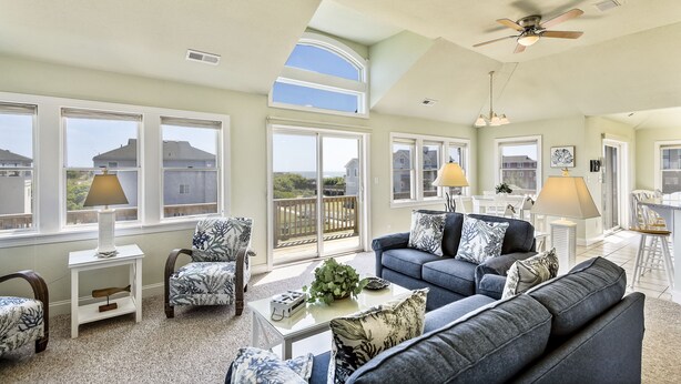 A spacious living room with a high ceiling, large windows, and a balcony. - WH816- Remarkable! 6 BRs, Private Pool, Hot Tub and even a Volleyball Court! (Corolla)