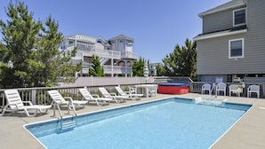 A swimming pool with lounge chairs and a red water slide. - WH816- Remarkable! 6 BRs, Private Pool, Hot Tub and even a Volleyball Court! (Corolla)
