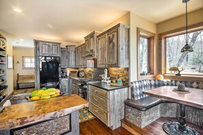 Une cuisine rustique avec des meubles en bois, un îlot central et un coin repas agrémenté d’une banquette.