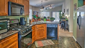 Una cocina con armarios de madera, un refrigerador de acero inoxidable, un microondas, una estufa y un lavavajillas.