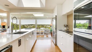 Una cocina moderna con armarios blancos, una isla grande y vistas al exterior.
