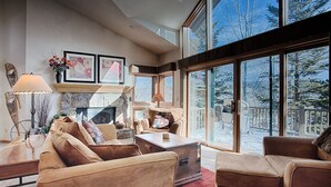 A spacious living room with a fireplace, large windows, and a view of a snowy landscape. - Quick Walk to Main St Breckenridge! Outdoor Hot Tubs/Pool! Attached Garage, Slee (Breckenridge)