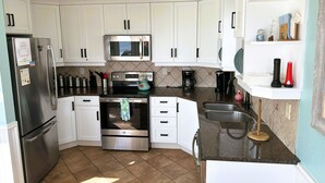 Uma cozinha moderna com armários brancos, eletrodomésticos de aço inoxidável e painel de azulejos.