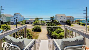 Eine Terrasse mit Sitzgelegenheiten mit Blick auf ein Wohngebiet und einen Strand.