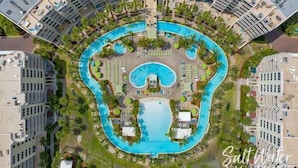 An aerial view of a hotel with a large central pool, surrounded by multiple smaller pools and sun loungers.