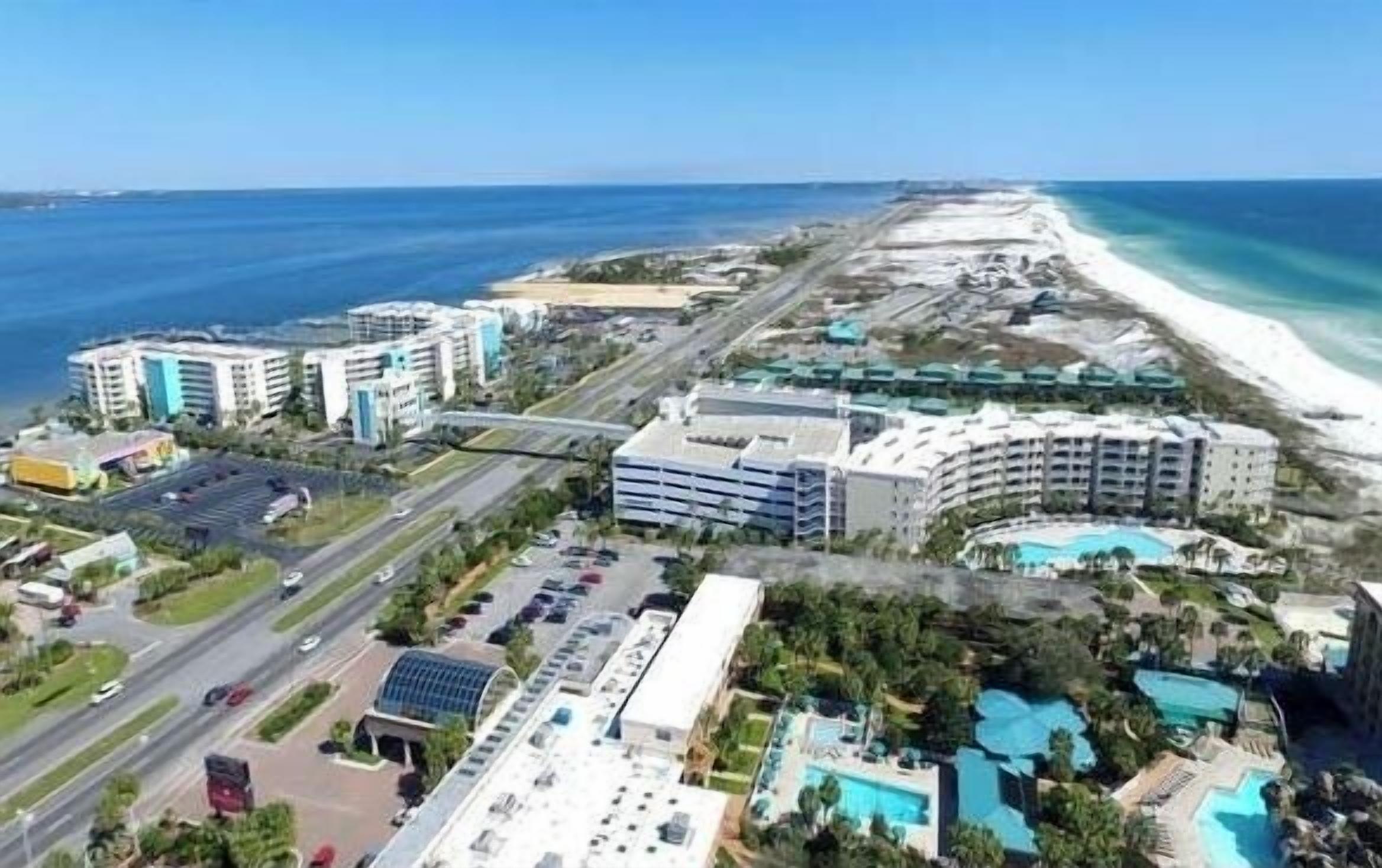 Vista aérea de una zona turística costera con varios edificios de hoteles, una carretera y una playa.