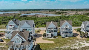 A coastal property with multiple two-story houses featuring balconies and a view of the beach and water.