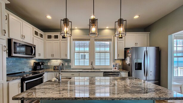 A modern kitchen with granite countertops, stainless steel appliances, and pendant lighting.