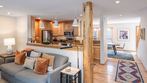 A modern kitchen with wooden cabinets, stainless steel appliances, pendant lighting, and a dining area with a table and chairs. - Wind River 3: Teton Village-Walk to Ski/Lift Sleeps 10- Pool / Hot Tub Access (Teton Village)