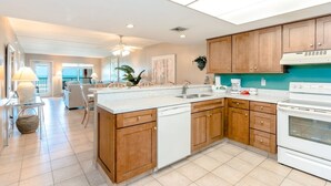 Una cocina moderna con armarios de madera, un lavavajillas blanco y una estufa blanca.