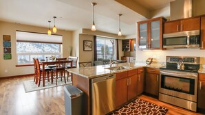 Una cucina moderna con elettrodomestici in acciaio inossidabile, mobili in legno e un'area pranzo con vista sull'esterno.