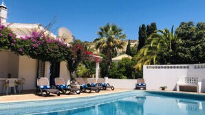 A pool area with lounge chairs, a white wall, and a satellite dish. - Charming Villa with Heated Pool & Large Garden near Sandy Beach, Hiking and Golf (Praia da Luz)